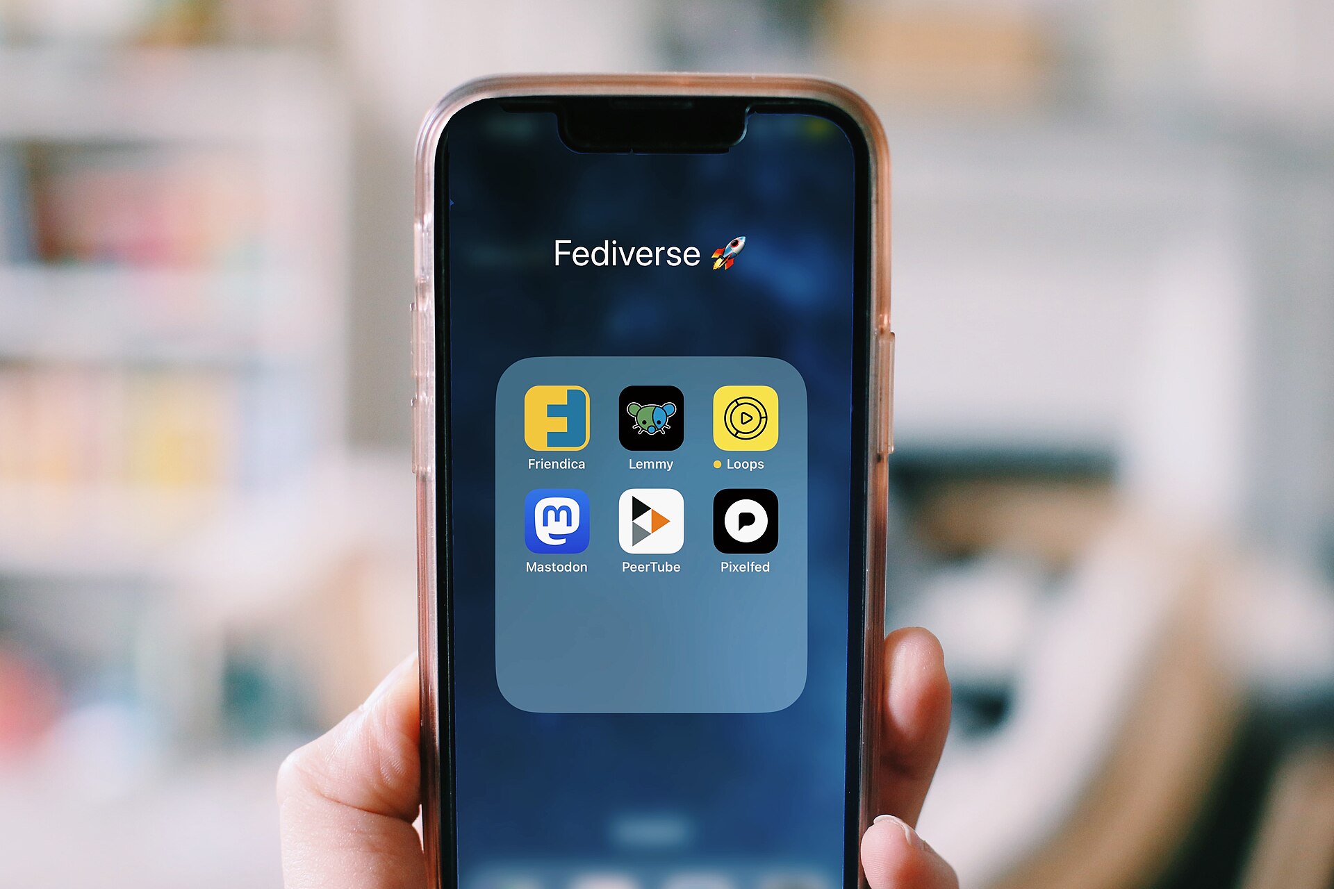 main tenant un smartphone affichant plusieurs applications, écran de sélection
