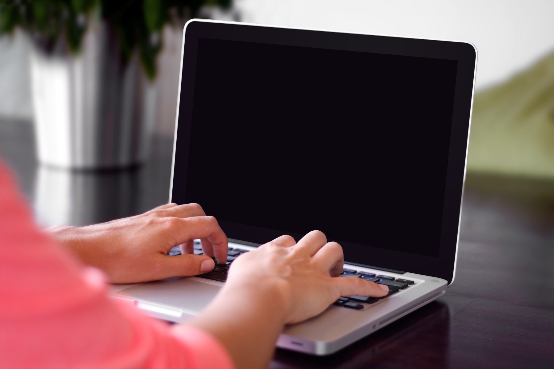 personne qui tape sur le clavier d'un ordinateur portable, mains posées sur les touches, avant de relire un document