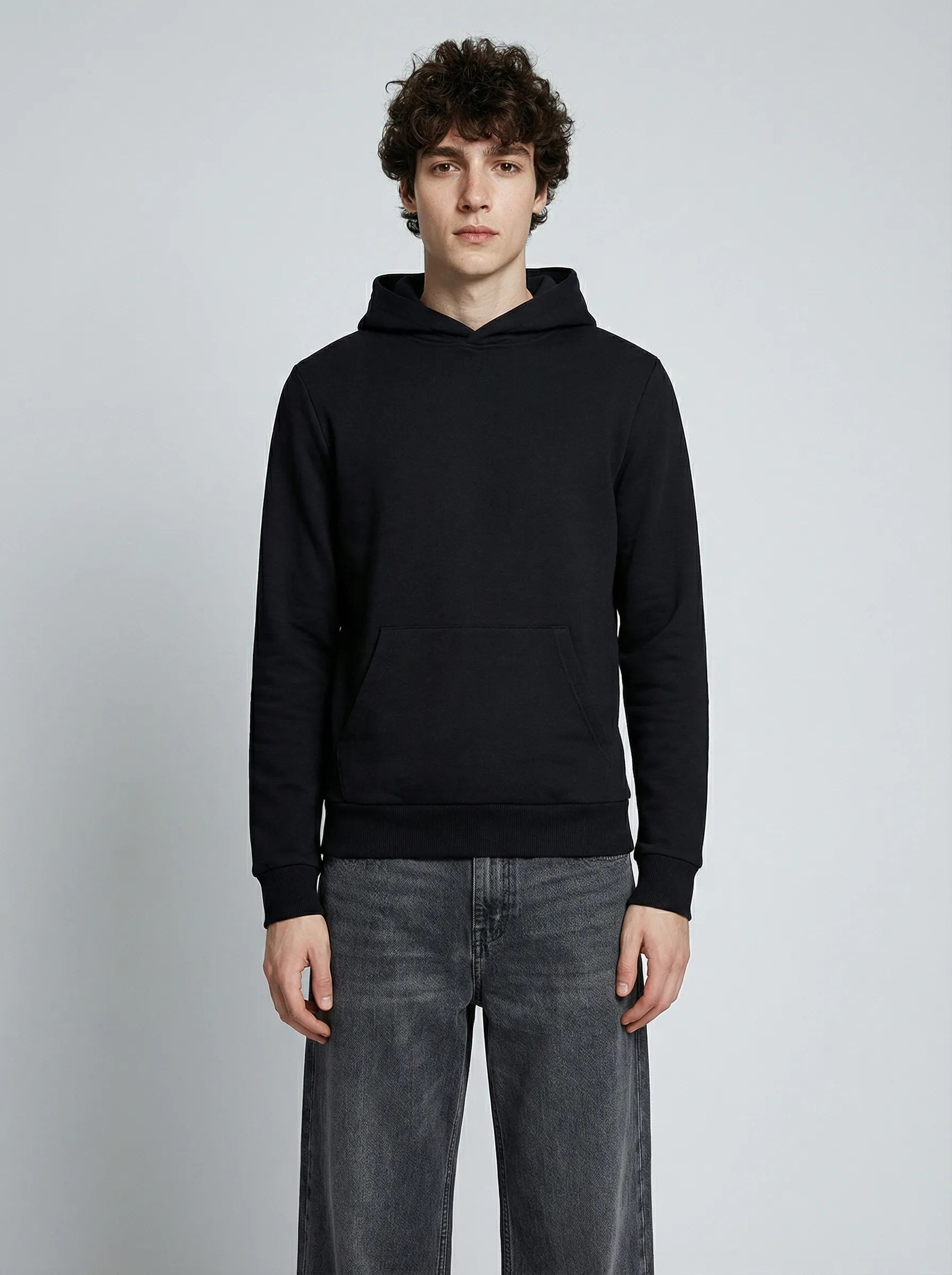 Homme portant un hoodie noir à capuche, mains dans les poches