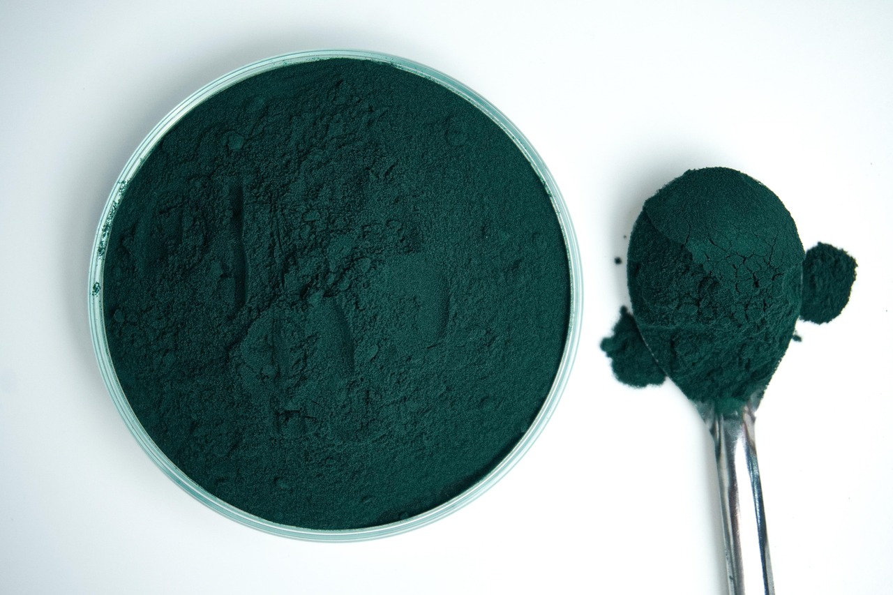 Poudre verte avec une cuillere doseuse, boisson en poudre