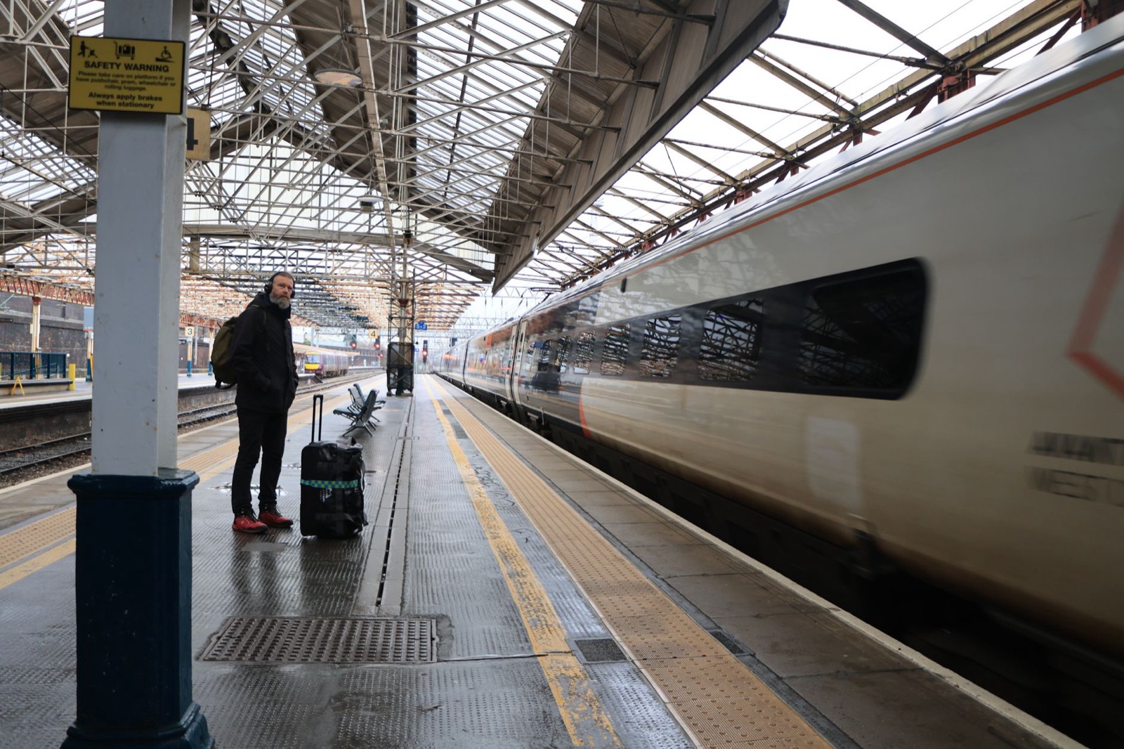 Voyageur avec valise sur un quai de gare attendant son train